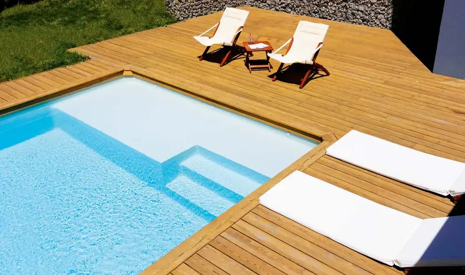 Ein Swimmingpool an einer Holzterrasse mit Sonnenstühlen zum Relaxen